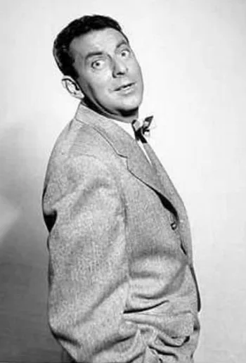 Black-and-white portrait of George O'Hanlon turning toward the camera in a tweed jacket and bow tie.