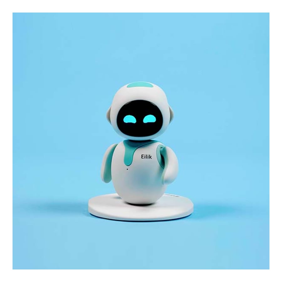 Small white and teal Eilik robot with a black screen face and blue eyes, standing on a round white base against a light blue background