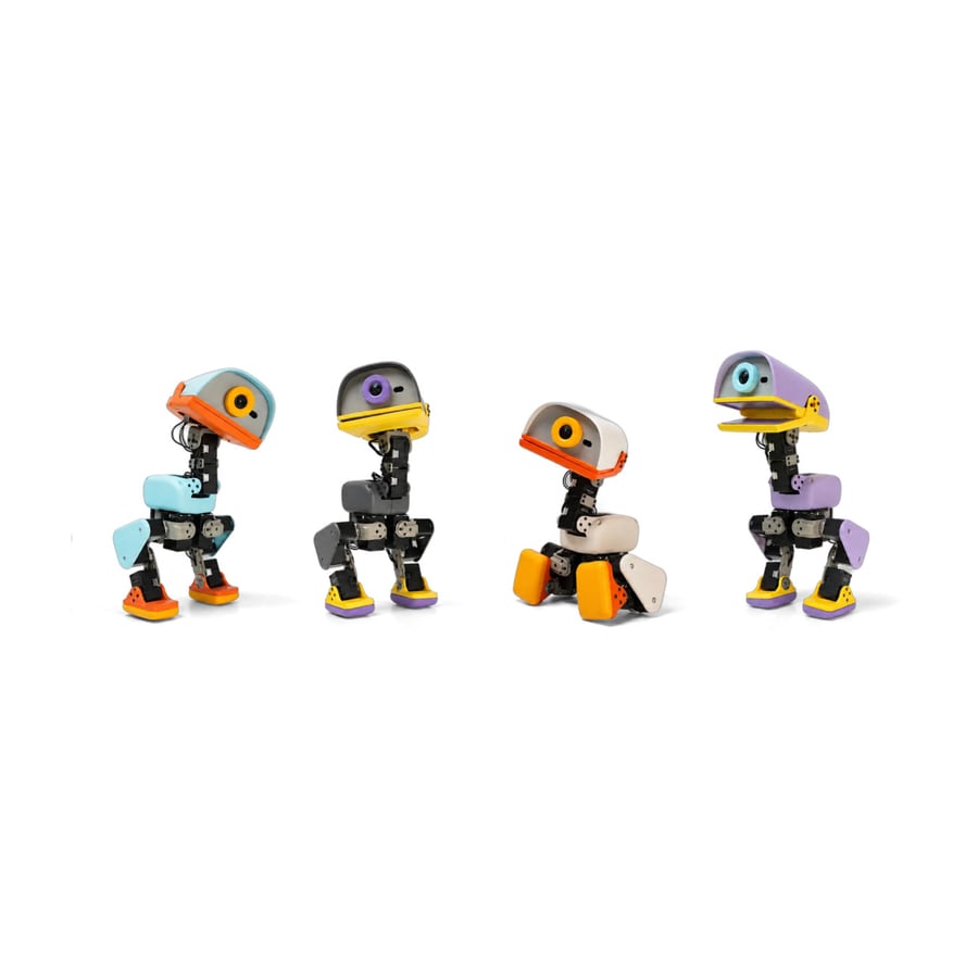 Four small two-legged Microduck robots in a row, each with a duck-shaped head in orange, grey, yellow or lavender