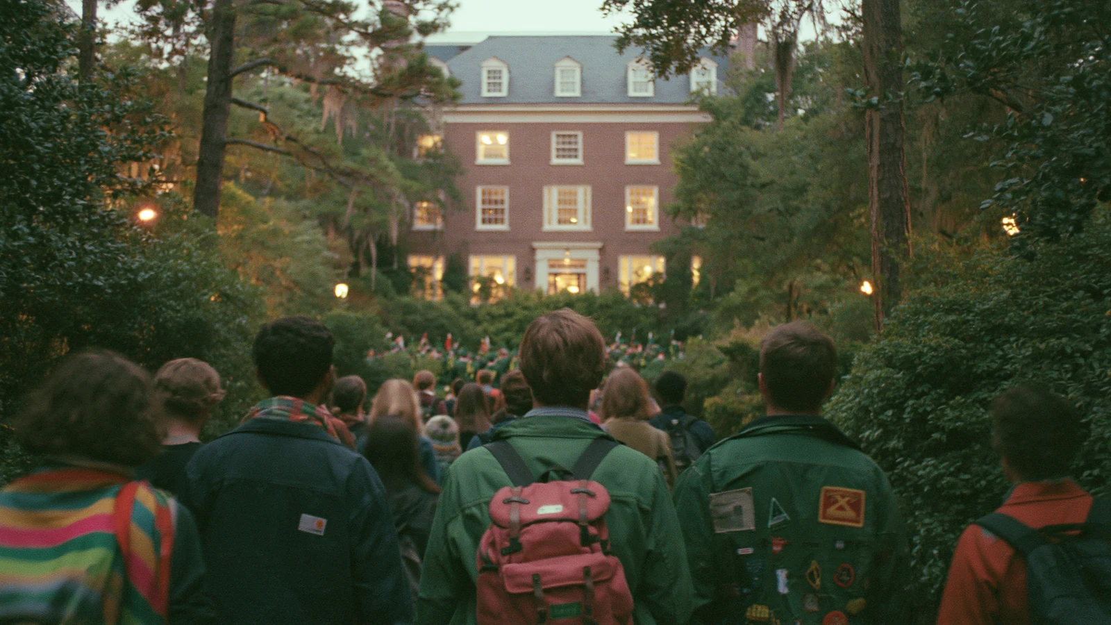 A loose procession of college friends walking from a shared house toward a night football game