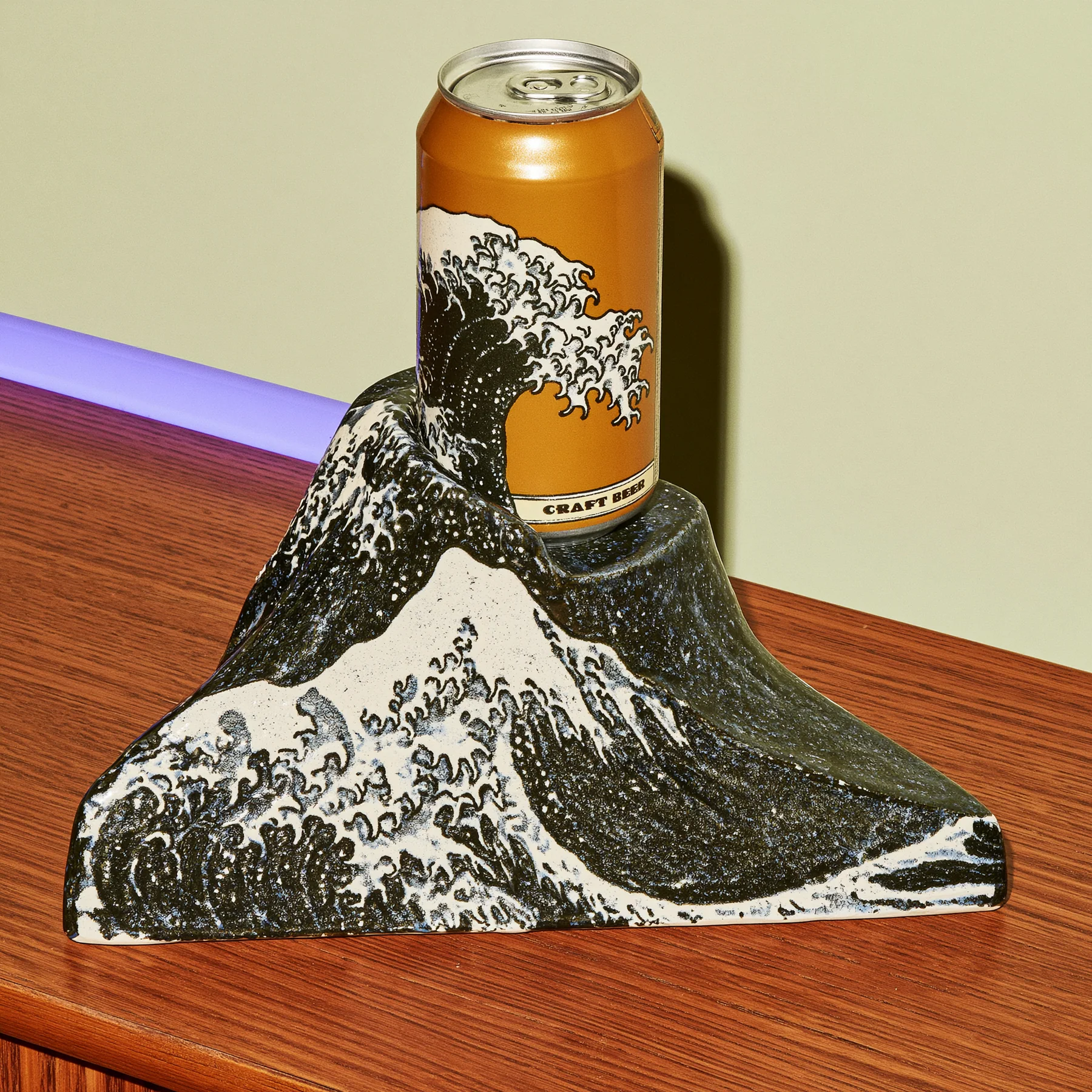 A black and cream pedestal patterned with a great wave and supporting an amber can