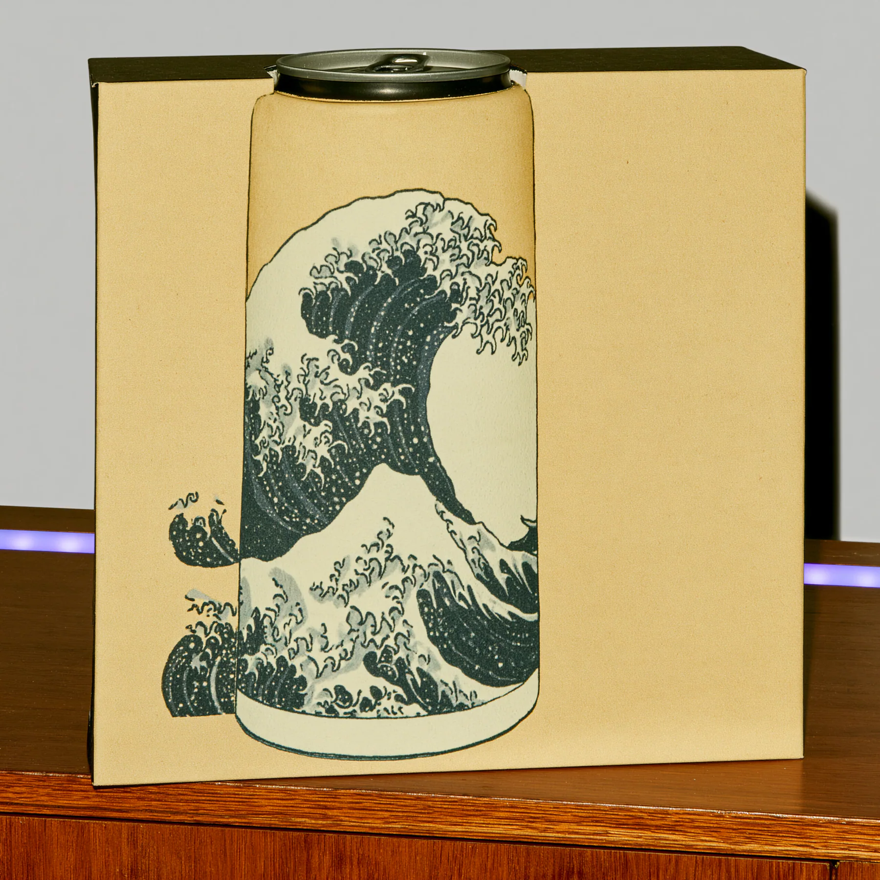 A can printed with a classic ocean wave sits inside a precisely cut cardboard window